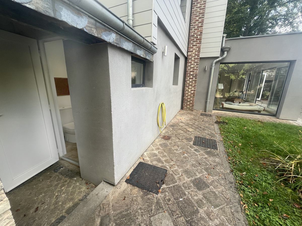 L’accès au second WC depuis le jardin : la porte ouverte au bout de l’allée pavée, le long de la maison.