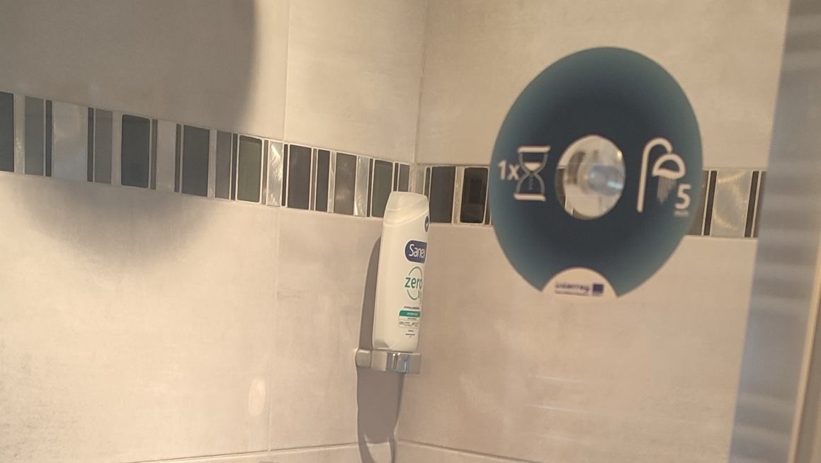 Le stick du programme sur la paroi de la douche : un sablier et une pomme de douche, 5 minutes.