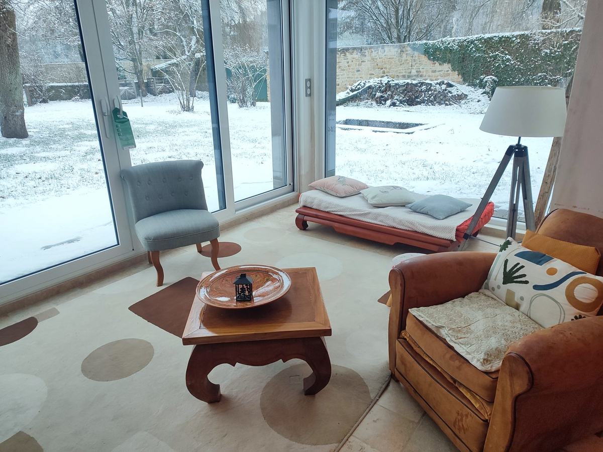Le salon en hiver, vue par les baies vitrées sur le jardin enneigé.